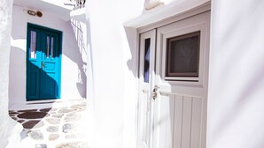 A narrow pathway with stone steps leading to a white building with a blue door and a white door. - Windmills Suite by Opus (Mykonos)
