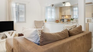 Ett vardagsrum med en soffa, en tv och ett köksområde i bakgrunden.