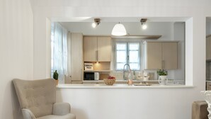 Ett modernt kök med en central köksö, en matplats med en stol och en soffa.