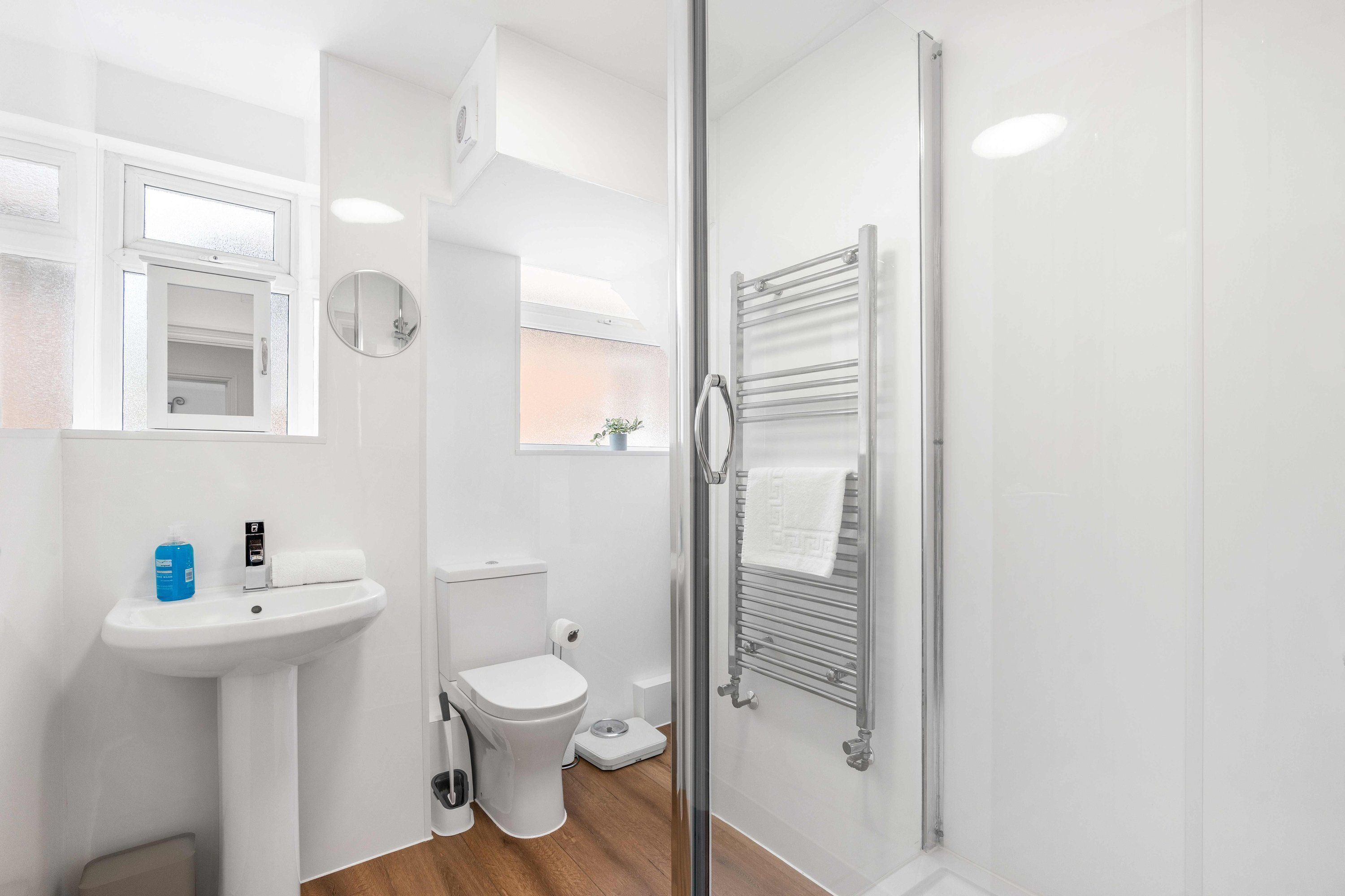Een moderne badkamer met een wastafel, toilet en douchecabine van glas.
