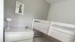 Un letto a castello con scrivania e lampada, una piccola pianta e un quadro appeso al muro.