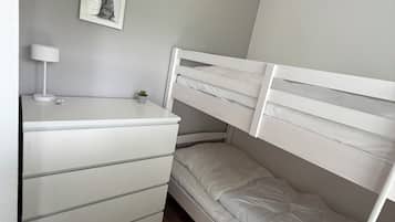 A bunk bed with a desk and a lamp, a small plant, and a framed picture on the wall.