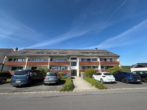 Ein mehrstöckiges Wohngebäude mit Parkplatz davor.