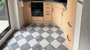 Una cucina con mobili in legno, un forno nero e un pavimento a scacchi.