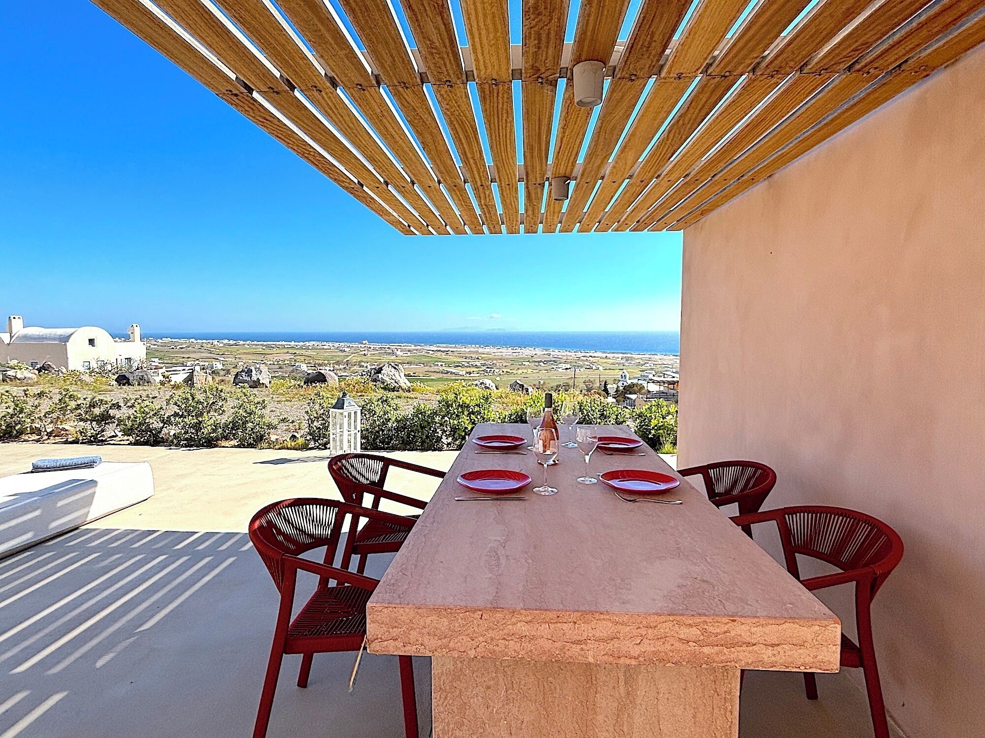 Una terraza con una mesa preparada para cuatro personas, con vistas al paisaje costero.