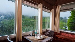 Een kamer met een ontbijt gedekt, een bankje en uitzicht op een groen landschap.