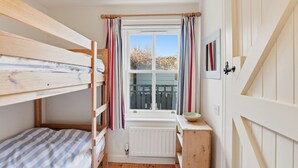 A small, cozy room with a window, a radiator, a wooden bed, and a small table with a bowl. - 5 Courtyard Cottages - North East Escapes (Embleton)