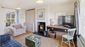 A cozy living room with a fireplace, a television, and a sofa. - 5 Courtyard Cottages - North East Escapes (Embleton)