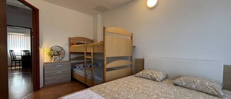 A bedroom with bunk beds, a desk, a chair, and a bedside table.