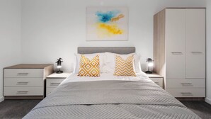 Ein Schlafzimmer mit Bett, Nachttischen, einem Kleiderschrank und einem Wandbild.