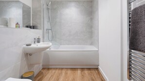 Ein modernes Badezimmer mit einem weißen Waschbecken, einer Badewanne und einer Dusche.