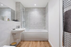 A modern bathroom with a white sink, a bathtub, and a shower. - City Point Aberdeen by Guestz (Aberdeen)