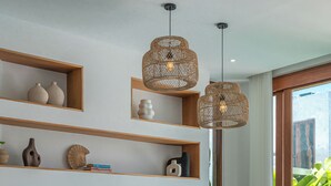 Ein modernes Wohnzimmer mit Flachbildfernseher, Holzregalen, einer Couch und einem Fenster mit Blick auf Grünflächen.