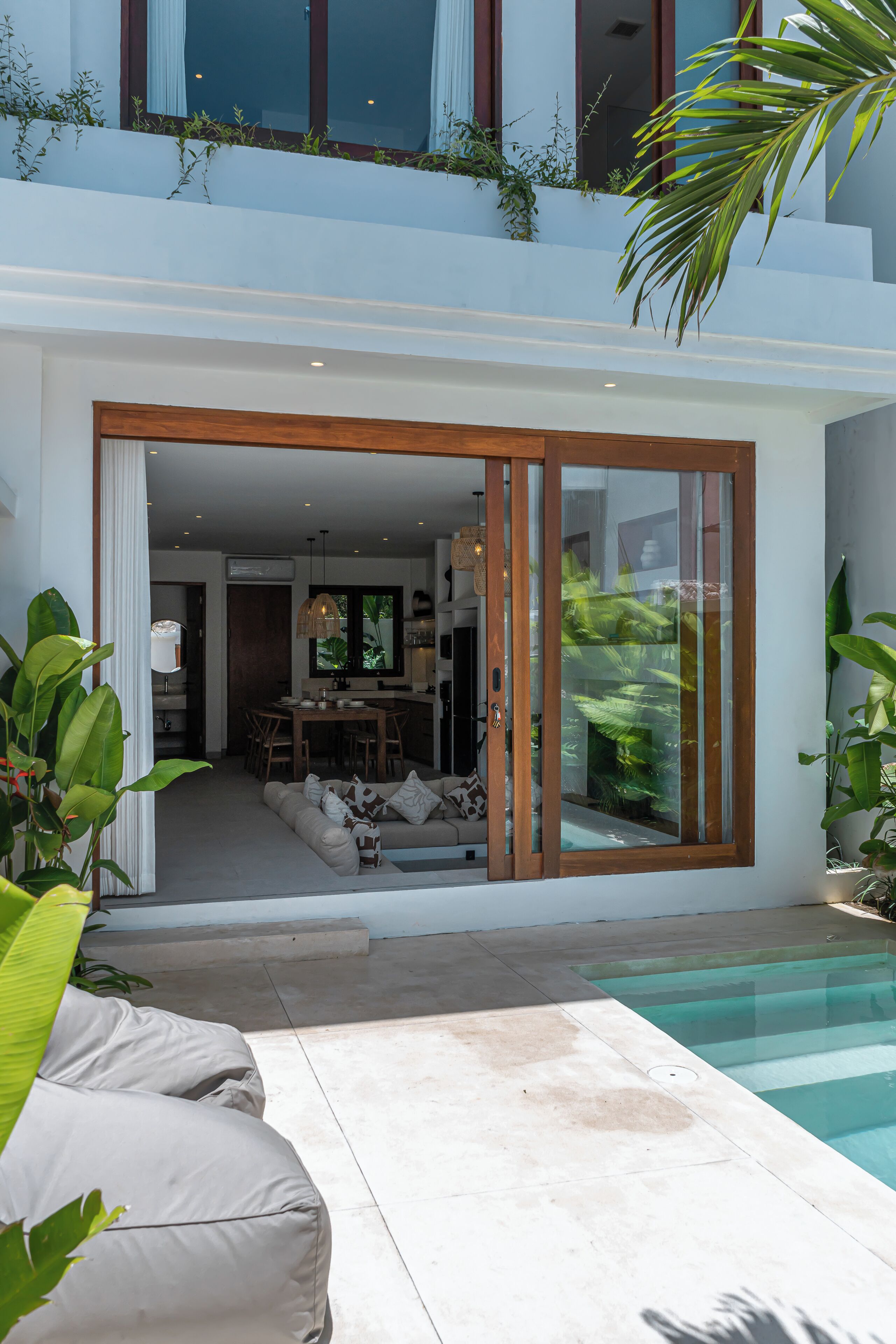 Una casa moderna con piscina, comedor y sala de estar con sofá.