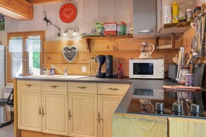 Una cocina con armarios de madera, microondas, cafetera y varios utensilios de cocina.