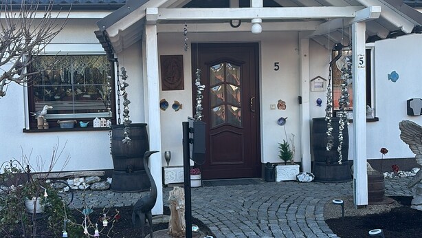 A house with a dark tiled roof, a front porch, and a number '5' on the wall. - Apartment 'Ferienwohnung Hühnergott' with Wi-Fi (Sassnitz)