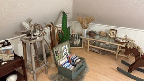 A room with a wooden floor, a bookshelf, a small table with decorative items, and a glass display case. - Apartment 'Ferienwohnung Hühnergott' with Wi-Fi (Sassnitz)