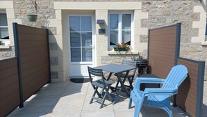 Un patio con mesa y sillas, una parrilla y una ventana con vistas.