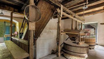 Un interior rústico con vigas de madera, un banco de madera y un barril grande de madera.