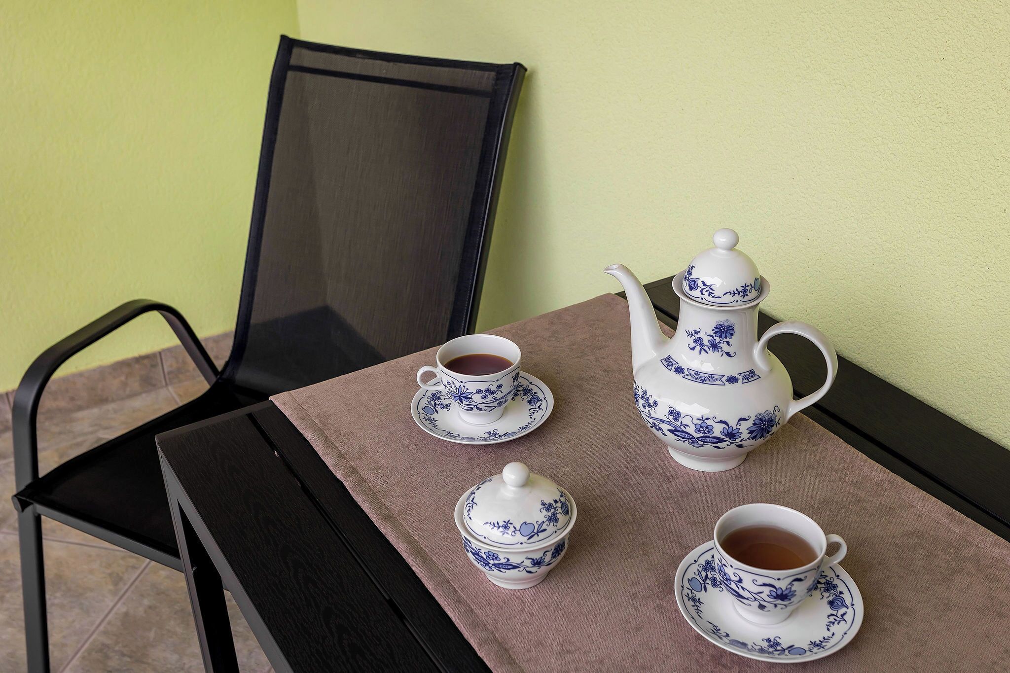 Een tafel met een theepot, twee kopjes en een schoteltje.