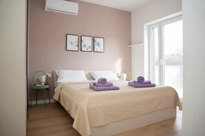 Ein Schlafzimmer mit Bett, Nachttisch, Wandaircondition und gerahmten Kunstwerken.