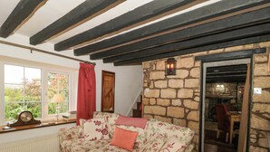 Ein gemütliches Wohnzimmer mit einer blumengemusterten Couch, einer Steinwand und einer Holztreppe.