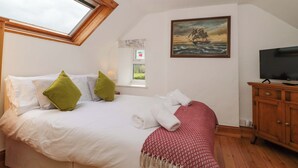 Ein Schlafzimmer mit Bett, Kissen, Fernseher, Gemälde und Fenster.