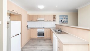 Una cucina moderna con mobili in legno, forno integrato, lavastoviglie e lavello.