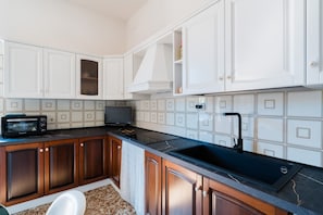 A kitchen with white cabinets, a black countertop, a microwave, and a sink.