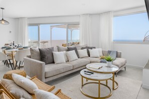 Ein modernes Wohnzimmer mit Sofa, Couchtisch und Essbereich.