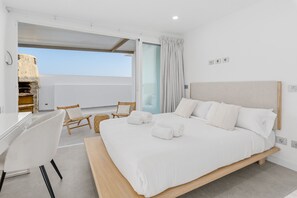 Ein Schlafzimmer mit Bett, Schreibtisch, Stühlen und Blick zum Himmel.