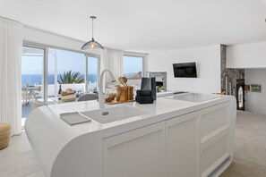 Eine moderne Küche mit einer großen Kochinsel, einem Essbereich mit Aussicht und einem Kamin.