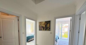 Un couloir avec un lit, un tableau et un balcon offrant une vue.