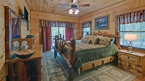 A wooden cabin bedroom with a bed, dresser, and a ceiling fan. - A River Runs Through It by Chatuge Home Concierge | Private Riverfront · Rustic Luxury Cabin · Fireplace · Deck Views · Kayak & Fish Access (Hayesville)