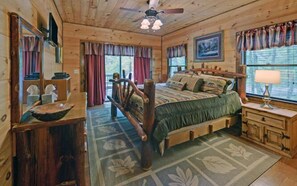 A wooden cabin bedroom with a bed, dresser, and a ceiling fan. - A River Runs Through It by Chatuge Home Concierge | Private Riverfront · Rustic Luxury Cabin · Fireplace · Deck Views · Kayak & Fish Access (Hayesville)