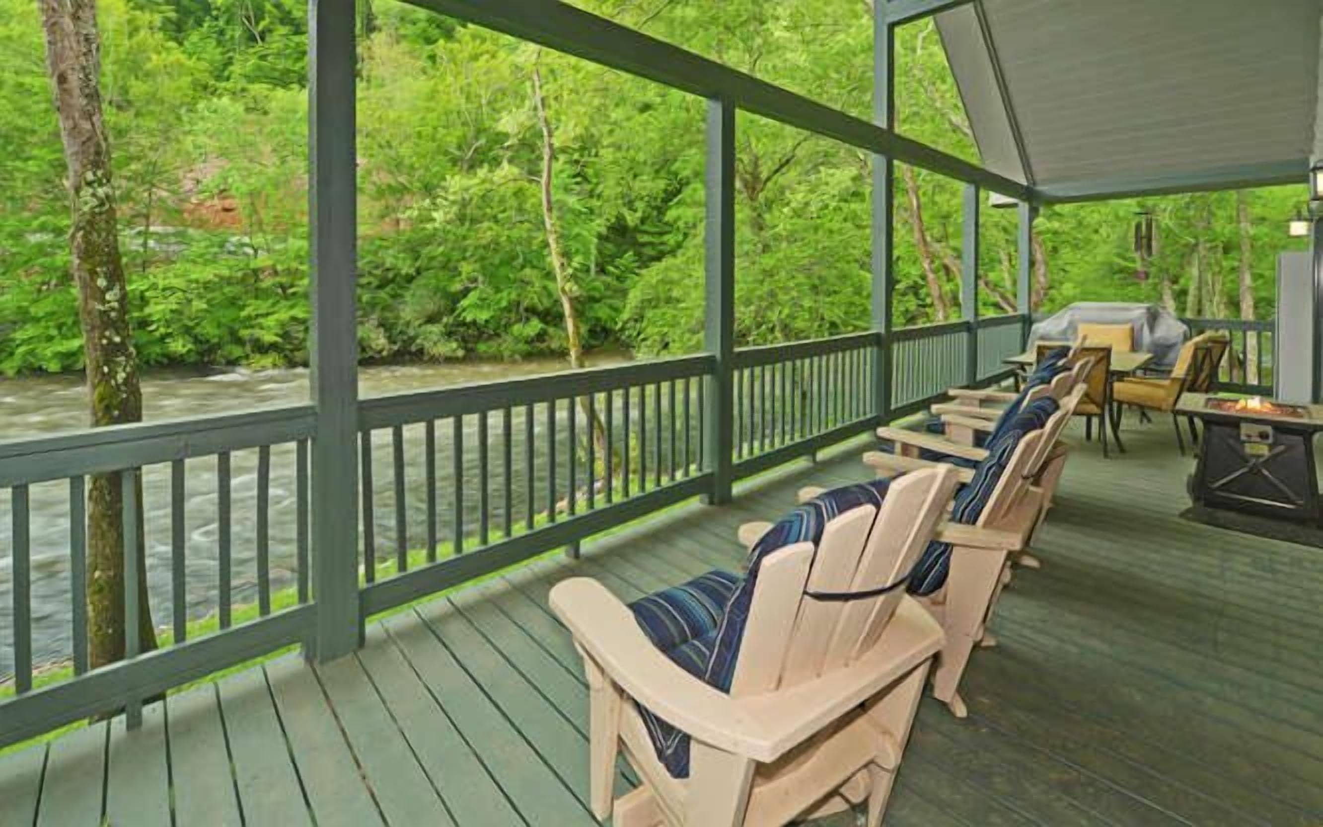 A covered outdoor area with Adirondack chairs and a grill.