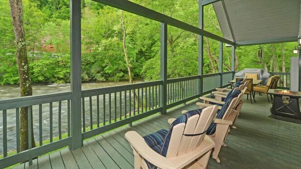 A covered outdoor area with Adirondack chairs and a grill. - A River Runs Through It by Chatuge Home Concierge | Private Riverfront · Rustic Luxury Cabin · Fireplace · Deck Views · Kayak & Fish Access (Hayesville)