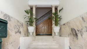 A marble staircase with two potted plants, leading to a wooden door. - Lisbon Uptown Rooms by Homing (Lisbon)