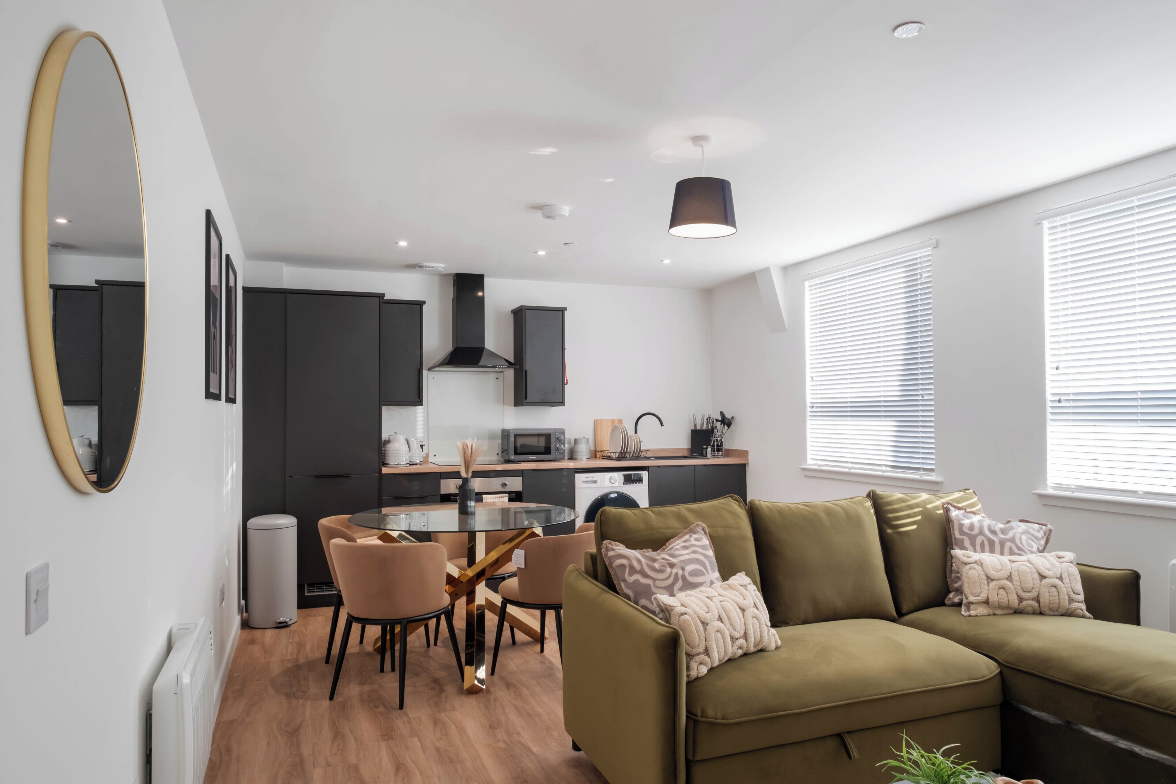 Un espace de vie moderne comprenant un coin repas, une kitchenette et un canapé agrémenté de coussins à motifs.