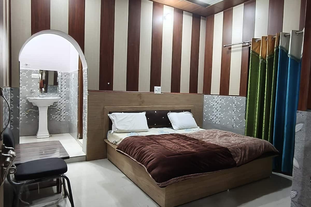 Un dormitorio con cama, tocador con espejo, lavabo y una silla.