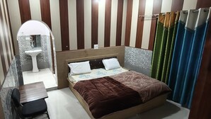 Une chambre à coucher comprenant un lit, un bureau, une chaise, une coiffeuse avec un miroir et un espace douche.