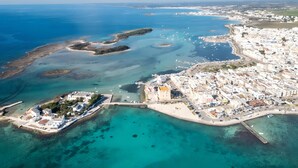 Vista aérea de uma cidade costeira com um porto de iates, praias de areia e uma mistura de edifícios residenciais e comerciais.