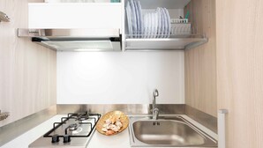 Uma cozinha moderna com fogão a gás, pia de aço inoxidável e escorredor de louça.