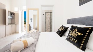 Een hotelkamer met een bed, kussens, een garderobe, een badkamer en uitzicht.