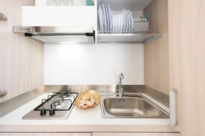 A modern kitchen with a gas stove, stainless steel sink, and dish rack.