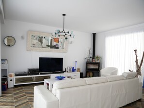 A living room with a white sofa, a flat-screen TV, a decorative mirror, and a black fireplace. - Super modern villa located 10 minutes by car from Palma city centre and Portixol (Palma de Mallorca)