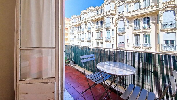 A balcony with a table and chairs, overlooking a row of buildings with balconies. - New! N&J -LE CATINAT - Spacious - Balcony (Nice)