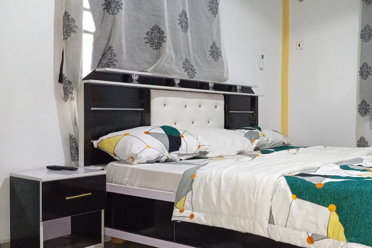 Un dormitorio con cama, mesitas de noche y cortinas.