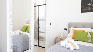 Ein Hotelzimmer mit Bett, Nachttisch, Spiegel und einer Tür, die auf einen Balkon führt.