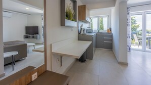 A modern kitchen with a built-in oven, a dining area with a bench, and a large window offering a view of the outdoors. - Modern vacation apartment with fantastic views and swimming pool (Crikvenica)